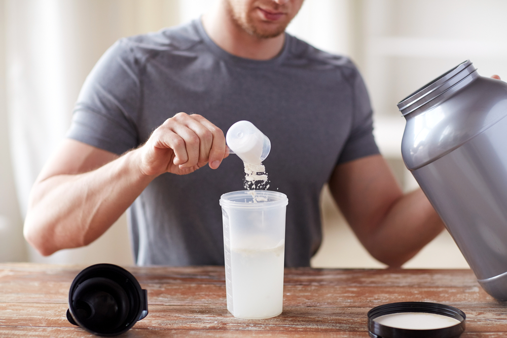 person adding Whey protein to water to make a shake