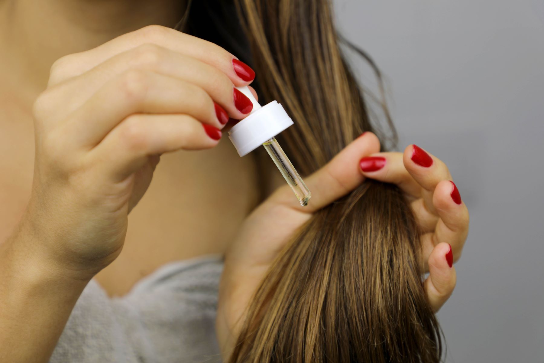 Woman applying olive oil directly to her hair