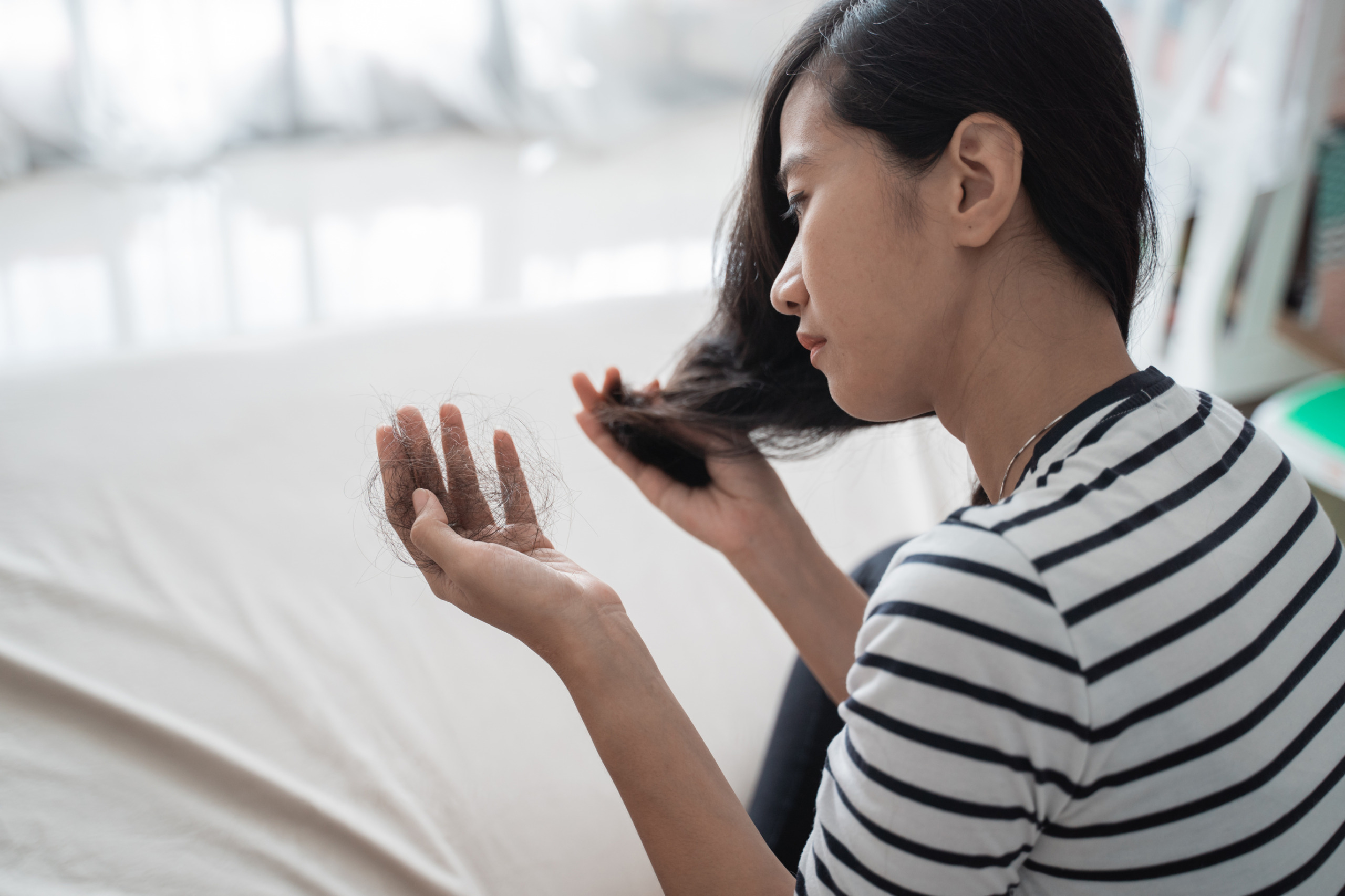 woman looks at shedded hair in hand