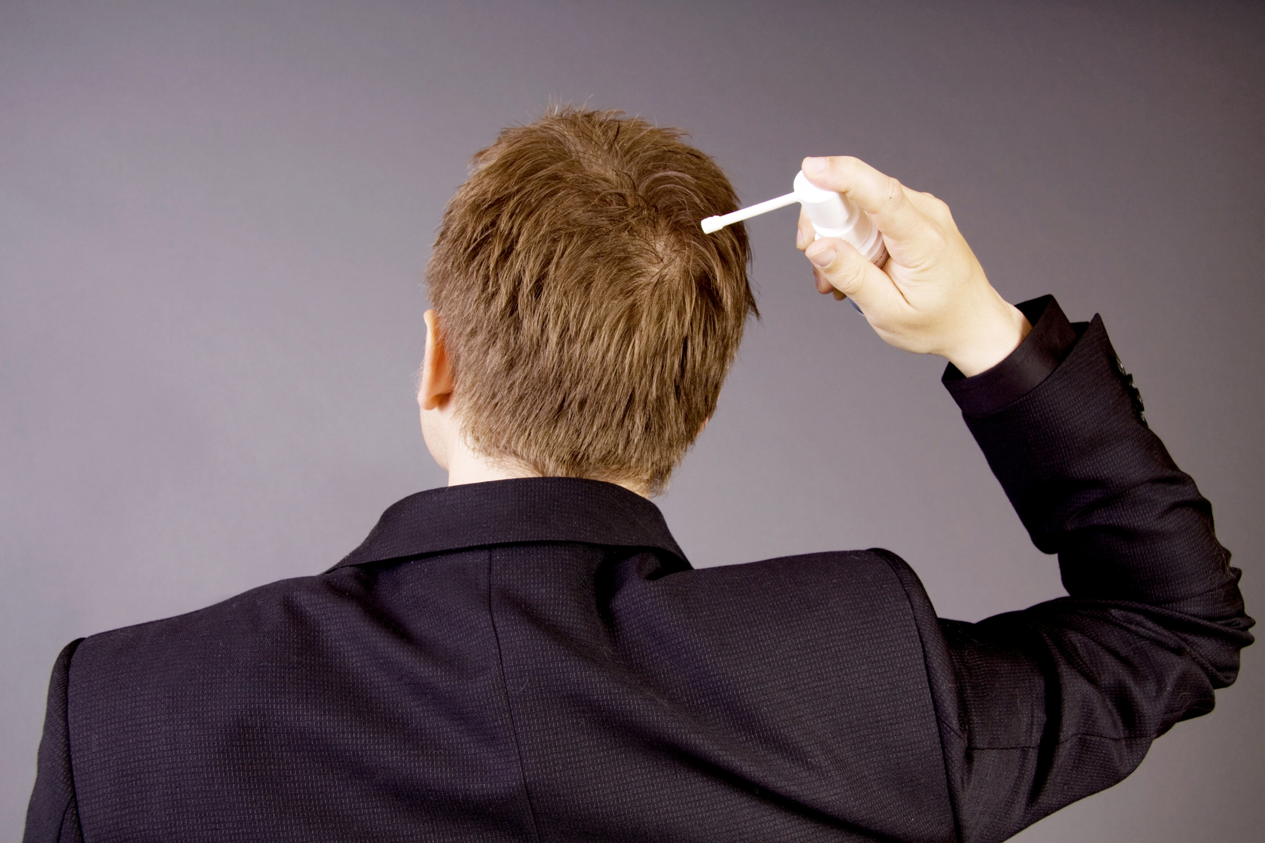 person applying a hair loss treatment to scalp