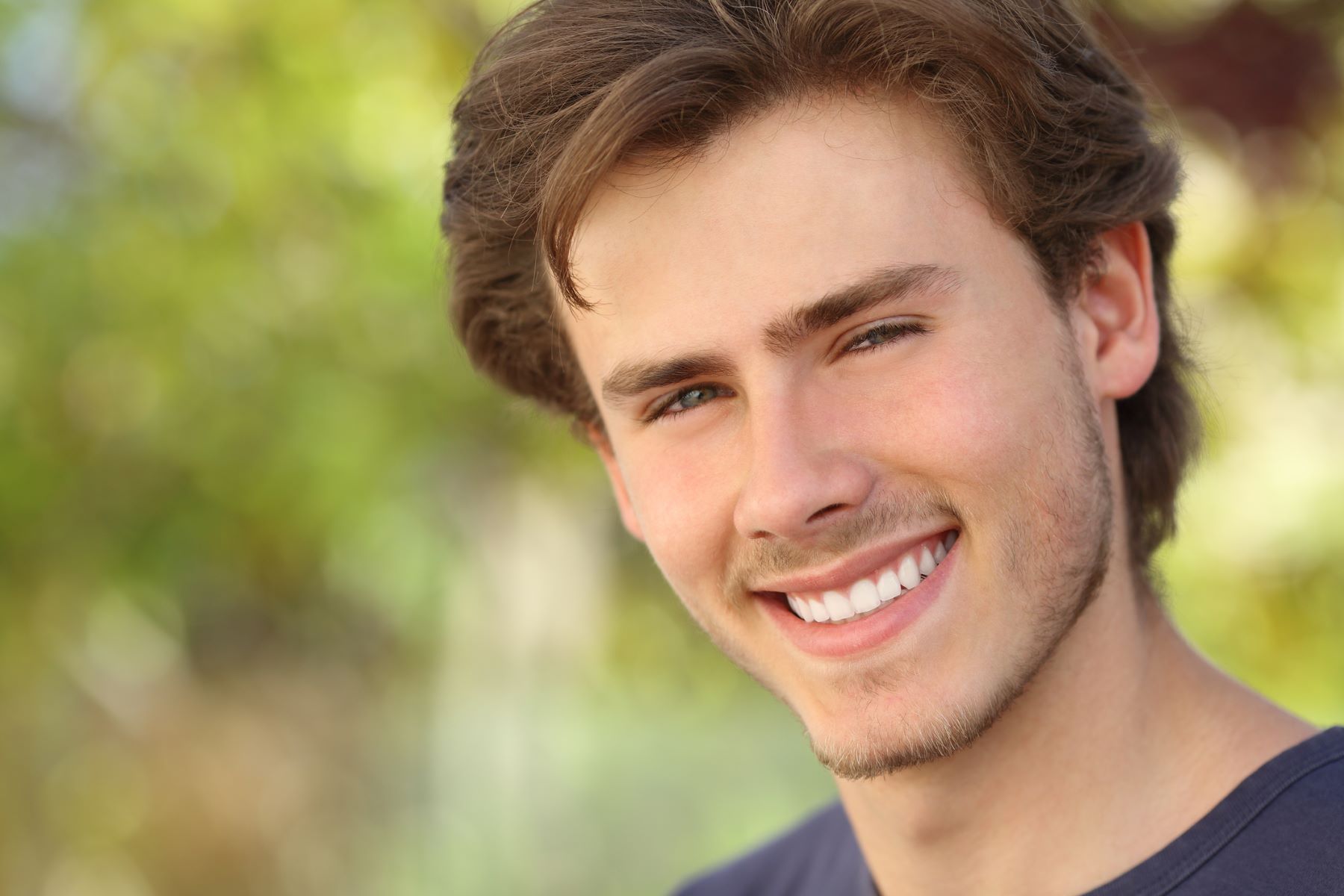 A smiling teenager, sporting a youthful, immature beard