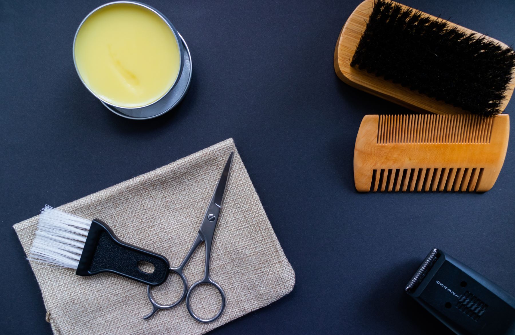 Beard trimming kit including scissors, beard trimmer, comb, brush, and beard balm