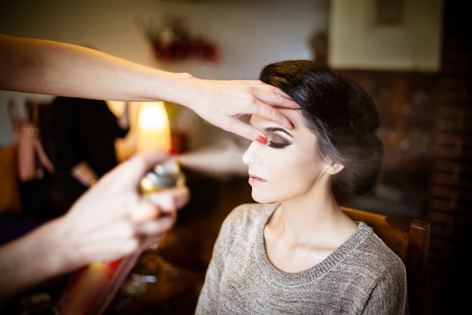 Woman inhaling hairspray during hair application