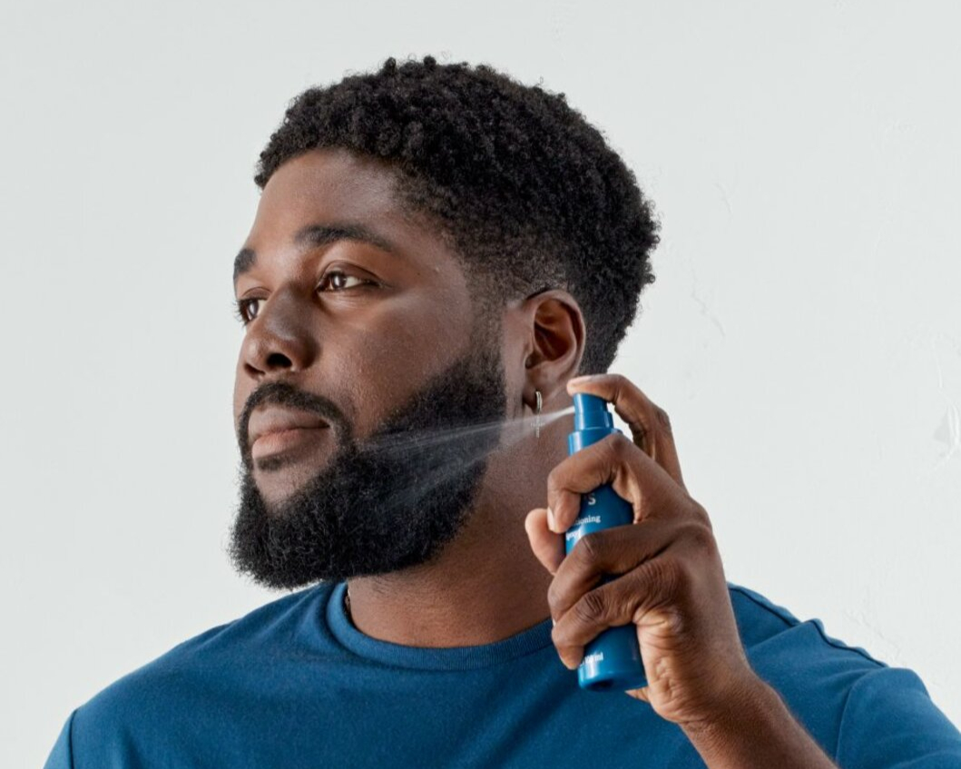 Young man using spray on his beard