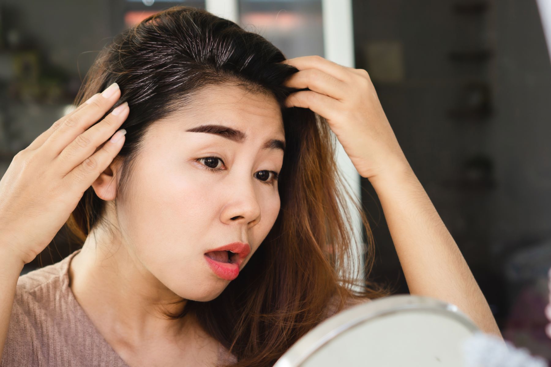 woman getting grey roots on dark brown hair prematurely