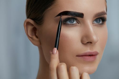 Woman applying brow tint to the eyebrow.