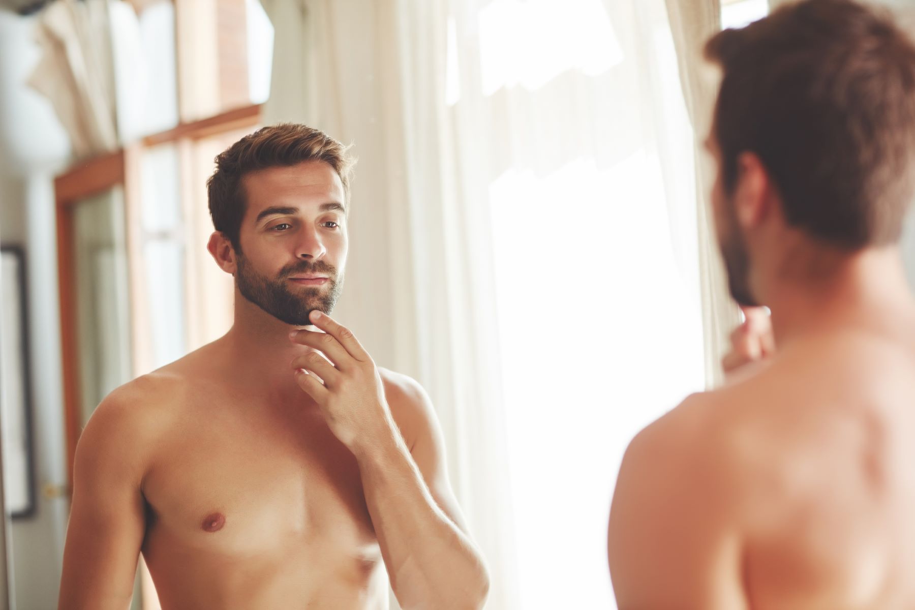 Man inspecting his beard bald spots