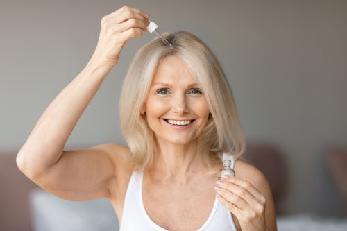 Woman applies essential oil to her scalp