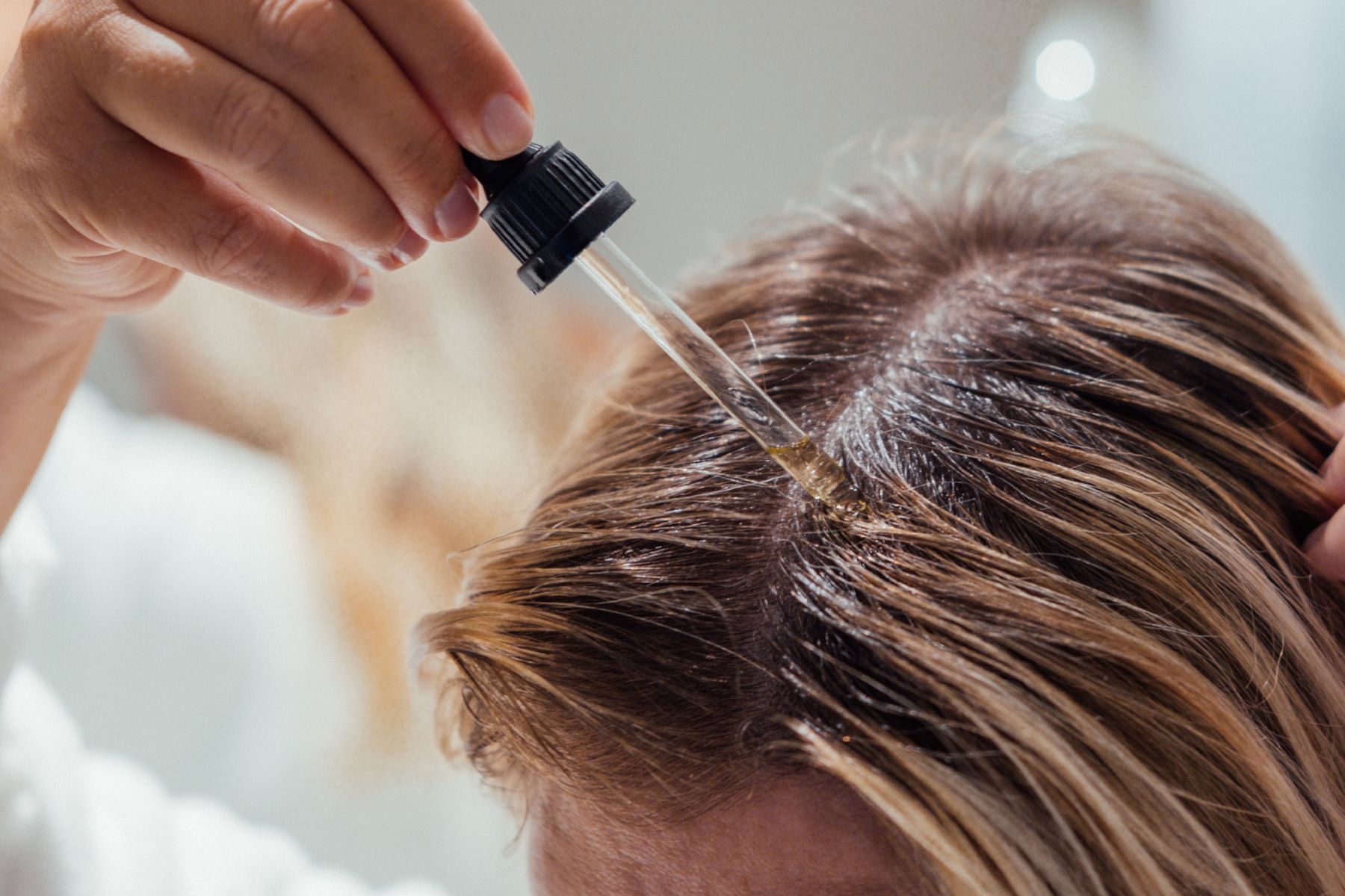 Woman applying essential oil to her scalp