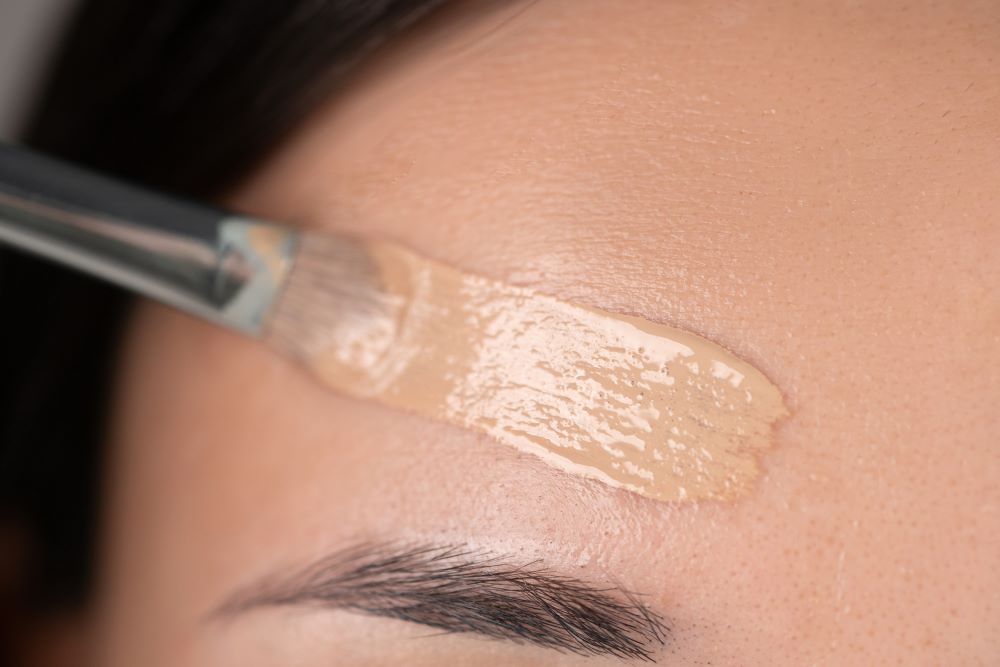 Woman applying makeup to her forehead