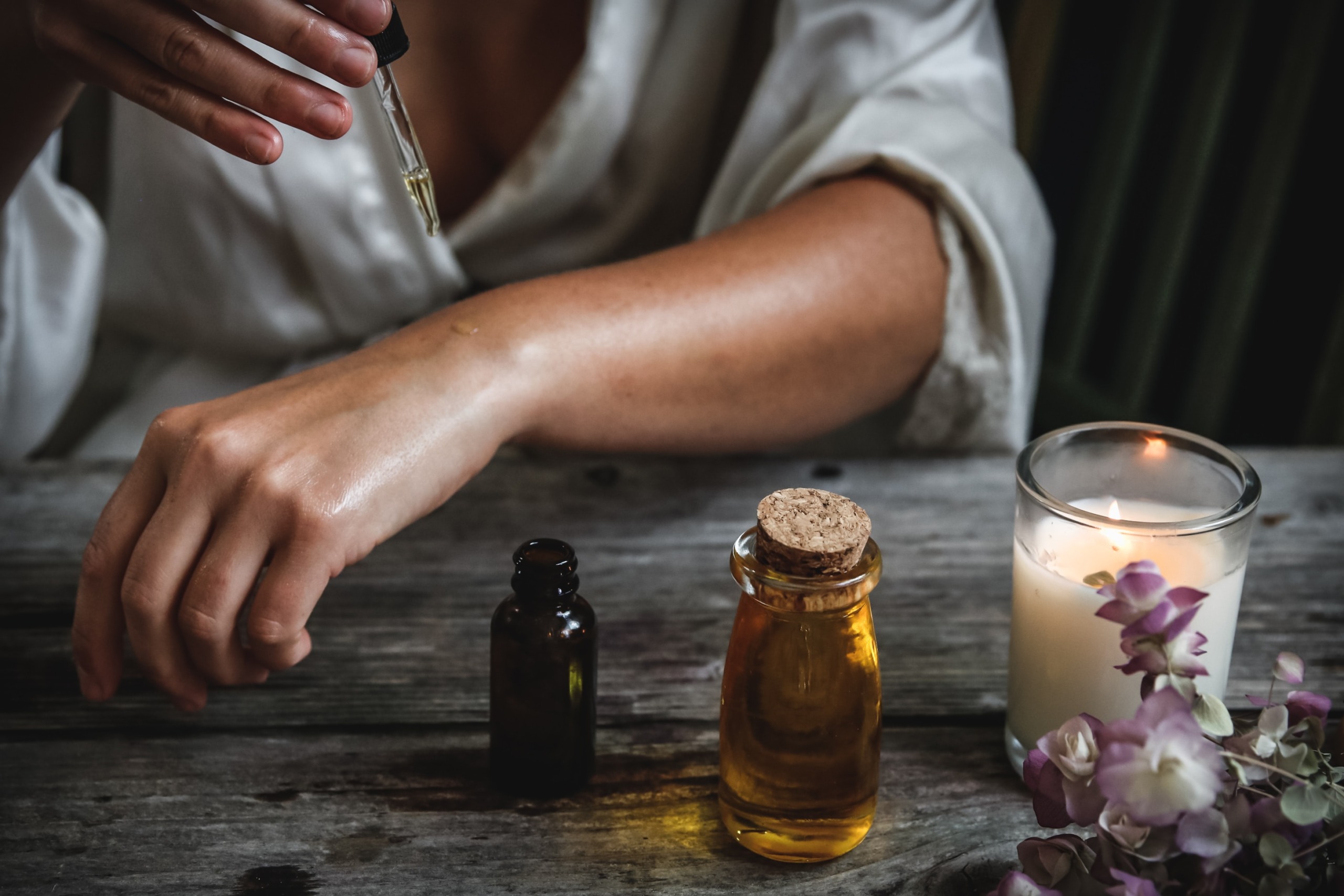 a person mixing an essential oil into a carrier oil like melted coconut oil or olive oil