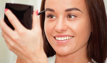 Woman Using An Eyebrow Pencil To Fill In Her Eyebrows.