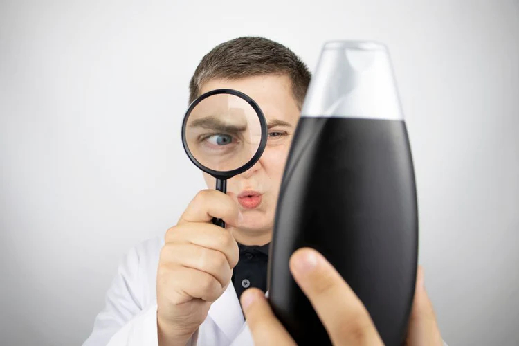 man reading ingredients on shampoo bottle