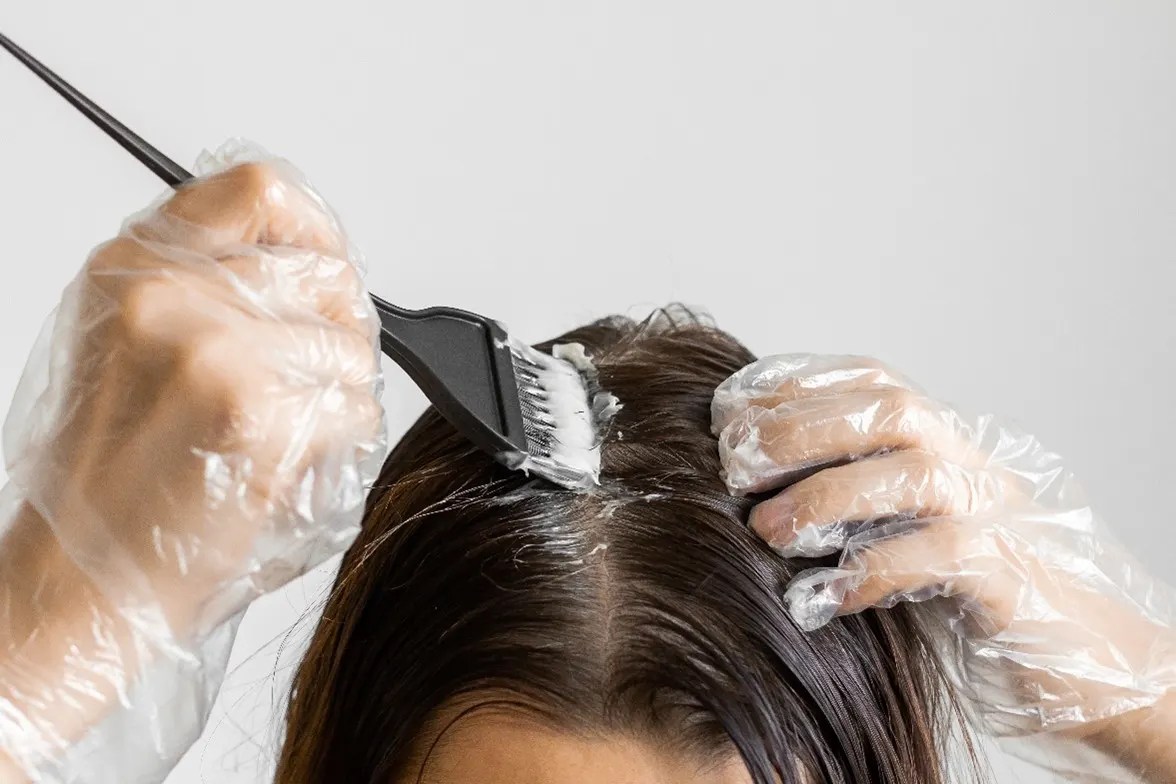 person applying hair dye onto their scalp