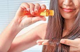 woman pouring oil on her hair